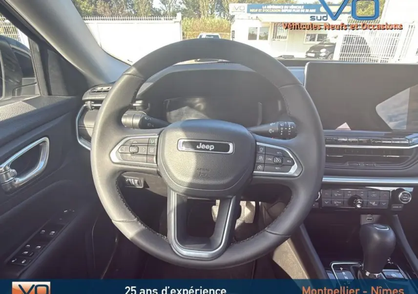 Vue centrée sur le volant du Jeep Compass 2024, montrant le tableau de bord et la console avec écran tactile.