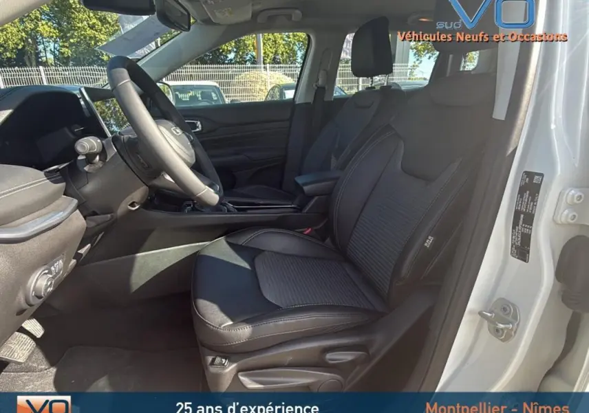 Intérieur noir du Jeep Compass 2024 blanc, vue côté conducteur ouverte montrant sièges et tableau de bord moderne.