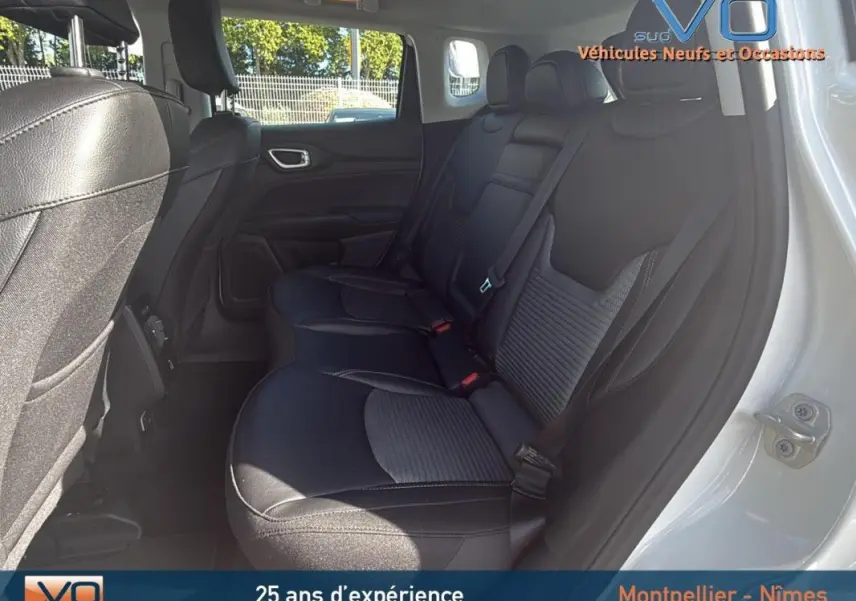 Vue intérieure arrière droite du Jeep Compass blanc 2024, sièges noirs en tissu et cuir avec ceinture de sécurité visible.