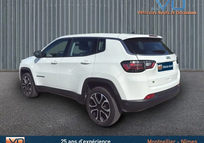 Vue 3/4 arrière gauche d'un Jeep Compass blanc 2024 avec jantes alliage 18 pouces et détails noirs contrastants.