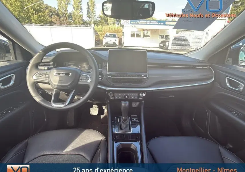 Vue intérieure frontale du Jeep Compass 2024 avec tableau de bord noir, écran tactile et volant multifonction.