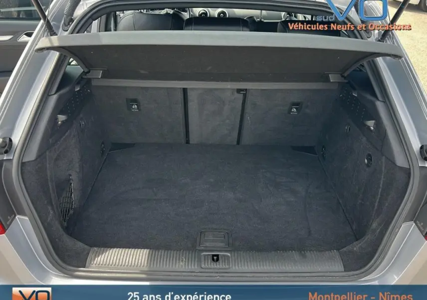 Coffre ouvert vu de l'arrière d'une Audi A3 Sportback gris clair, montrant un espace de chargement propre et spacieux.