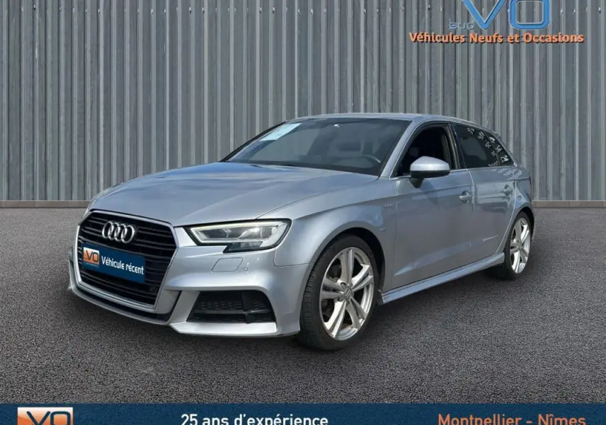 Audi A3 Sportback gris clair vue 3/4 avant droit avec jantes alliage et phares LED allumés.
