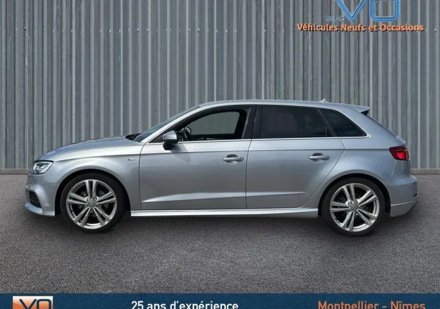 Profil côté gauche d'une Audi A3 Sportback gris clair de 2018 avec jantes alliage et châssis sport visible.