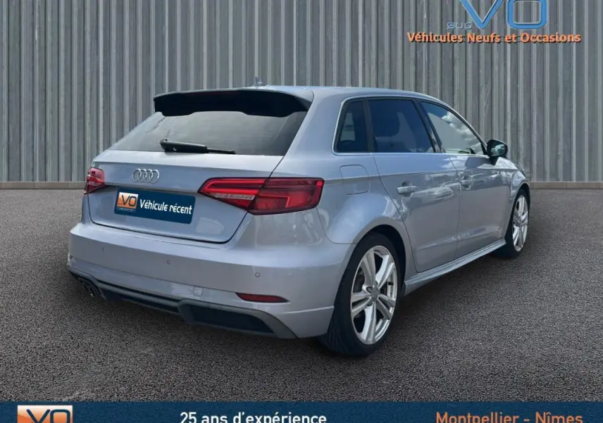 Audi A3 Sportback gris clair vue 3/4 arrière droit, avec jantes alliage et feux arrière LED distinctifs.