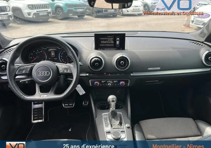 Vue intérieure avant de l'Audi A3 Sportback gris clair 2018, volant sport multifonctions et console centrale avec écran intégré.