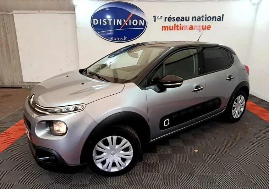 Citroën C3 gris clair vue 3/4 avant droit, avec protections latérales noires et jantes acier à enjoliveurs.