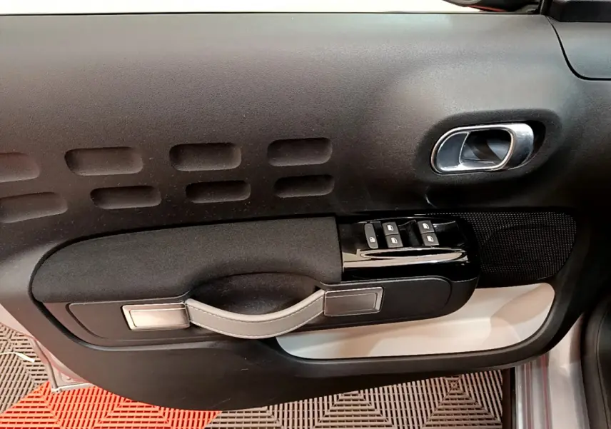 Intérieur côté conducteur de Citroën C3 gris clair 2019, panneau de porte avec commandes vitres et poignée design.