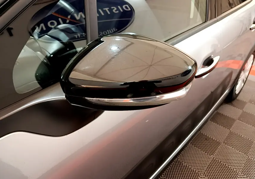 Rétroviseur noir brillant côté gauche d'une Citroën C3 gris clair 2019, avec poignée de porte visible en arrière-plan.