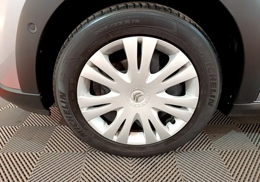 Gros plan sur la roue avant droite d'une Citroën C3 gris clair avec enjoliveur blanc et pneu Michelin.