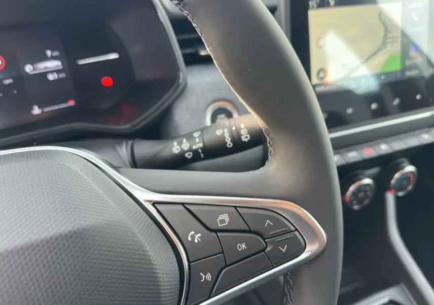 Gros plan sur le volant multifonctions en cuir de la Renault Clio DCI 100 Evolution, avec écran tactile et commandes au volant visibles.