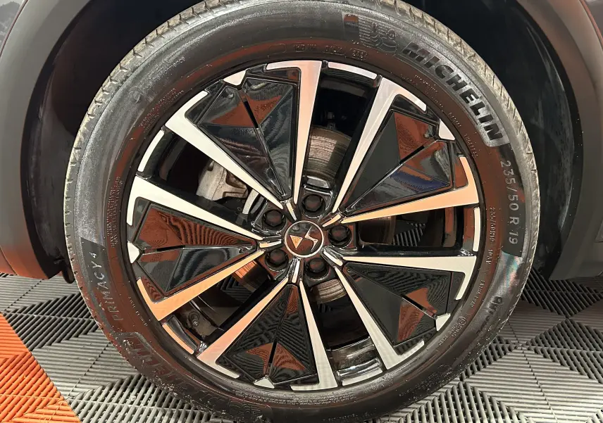 Gros plan sur la jante noire et argentée au design géométrique du DS7 gris titane, avec pneu Michelin visible.