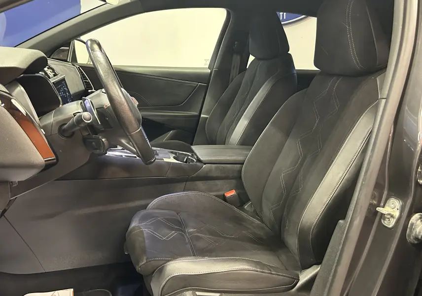 Vue intérieure côté conducteur du DS7 2024 gris titane, mettant en valeur les sièges en cuir Alcantara avec surpiqûres contrastées.