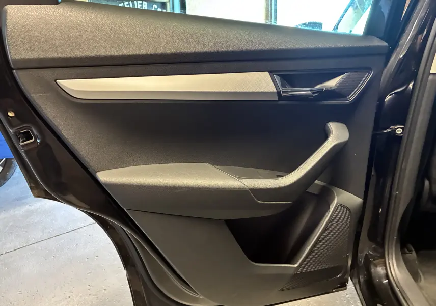 Vue rapprochée de la porte arrière gauche noire du Skoda Karoq 2024 avec insert décoratif argenté et poignée chromée.
