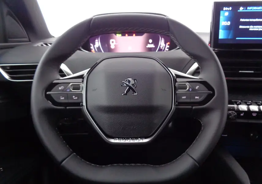 Volant cuir noir de Peugeot 3008 2023 avec commandes intégrées et tableau de bord numérique en arrière-plan.