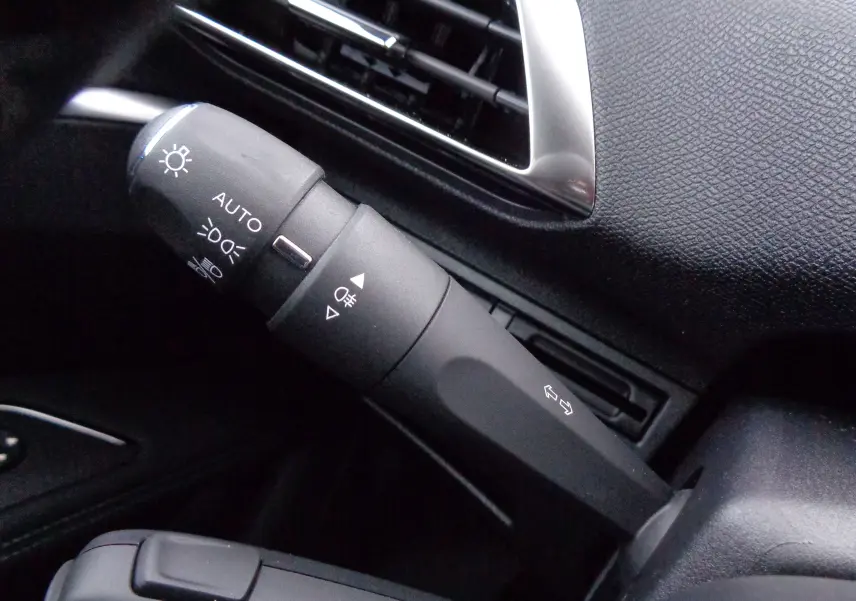 Gros plan sur la commande des feux et clignotants à gauche du volant dans l'habitacle noir du Peugeot 3008 bleu Celebes 2023.