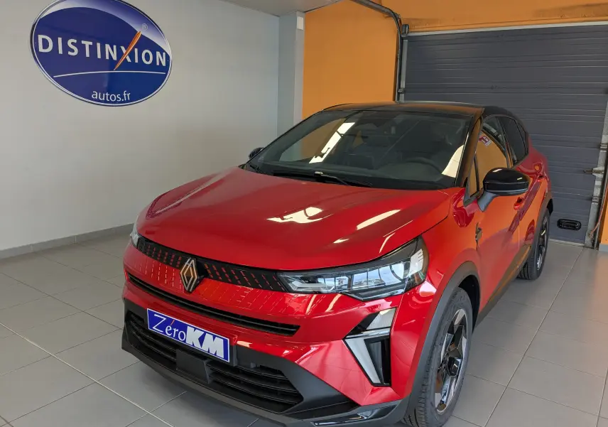 Renault Captur E-Tech hybride rouge flamme avec toit noir, vue 3/4 avant en intérieur showroom.