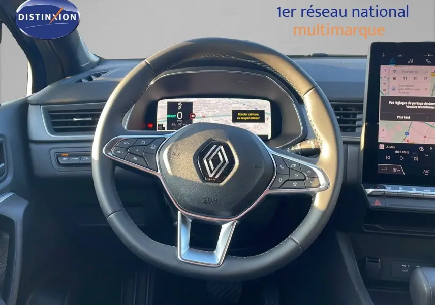 Vue rapprochée du volant noir du Renault Captur E-Tech Hybrid 2025 avec tableau de bord numérique et écran tactile.
