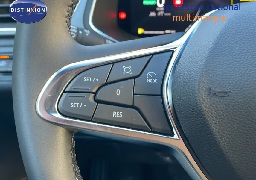Gros plan sur les commandes au volant du Renault Captur E-Tech bleu Iron Metal avec toit noir, affichage numérique en arrière-plan.
