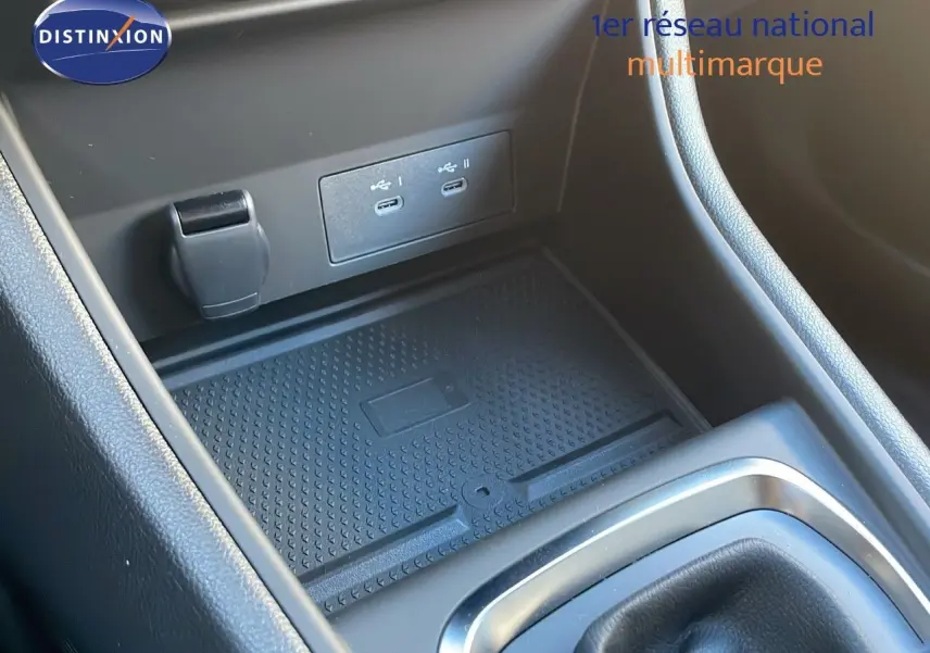 Gros plan sur la console centrale du Renault Captur bleu Iron Metal, montrant les ports USB et le tapis antidérapant.
