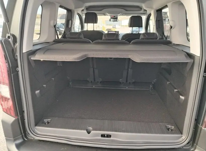 Vue arrière ouverte du coffre spacieux du Peugeot Rifter 2025 en Srikka Green, avec banquette arrière et cache-bagages visibles.