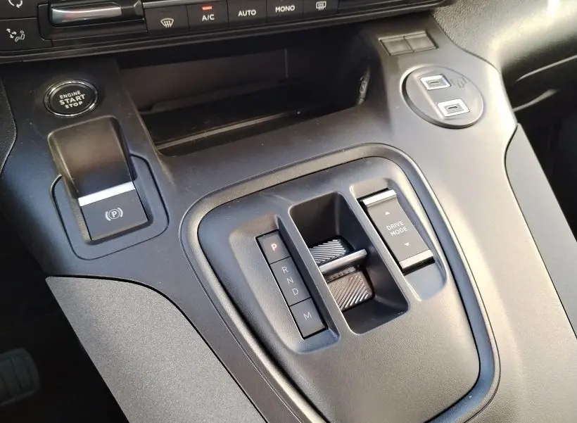 Gros plan sur la console centrale noire du Peugeot Rifter 2025, avec levier de vitesses automatique et bouton start/stop.
