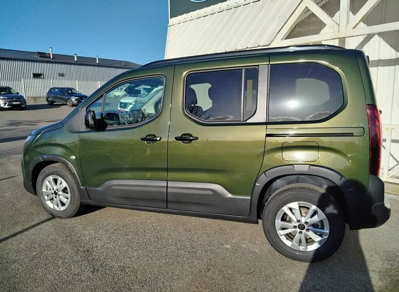Vue de profil côté gauche d'un Peugeot Rifter 2025 vert Srikka avec roues alliage et protections noires.