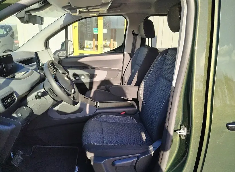 Vue intérieure côté gauche du Peugeot Rifter 2025 vert Srikka, montrant les sièges avant en tissu et le tableau de bord moderne.