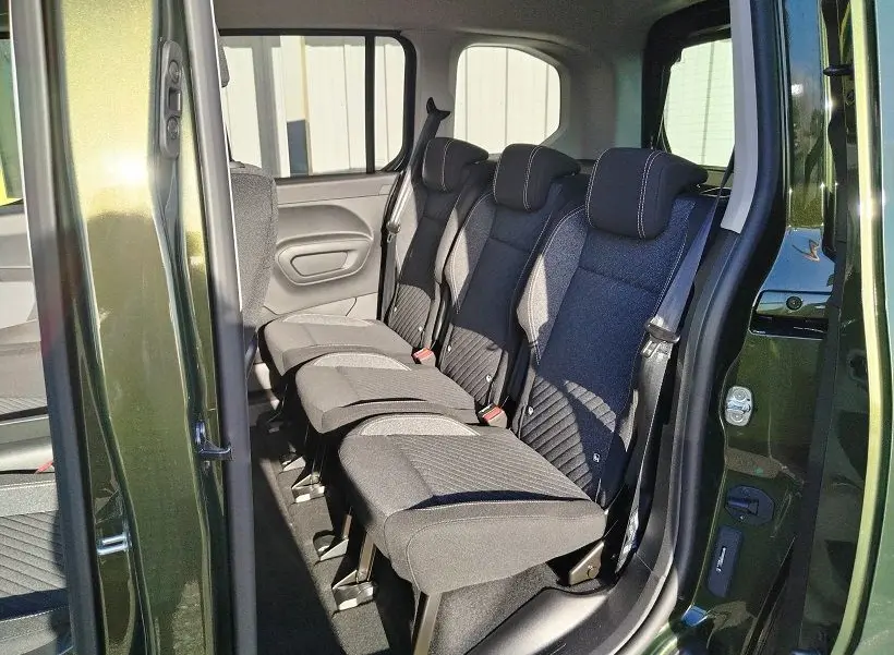 Vue intérieure côté droit sur les sièges arrière noirs du Peugeot Rifter 2025 en Srikka Green avec porte ouverte.