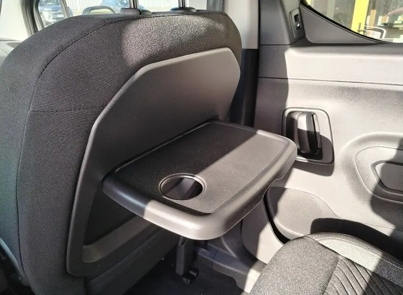 Détail intérieur côté droit du Peugeot Rifter 2025, tablette pliable noire fixée au dossier du siège avant.