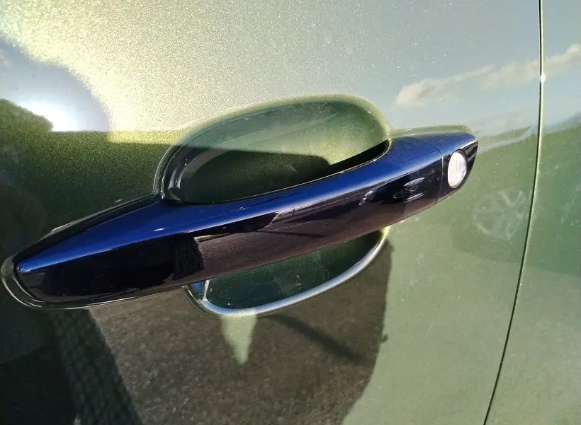 Poignée de porte noire en gros plan sur la portière côté gauche d’un Peugeot Rifter 2025 vert Srikka.