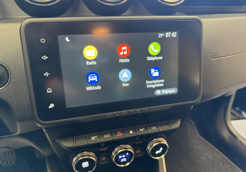 Écran tactile central du tableau de bord du Dacia Duster 2022 avec interface multimédia et commandes climatisation.