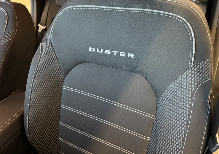 Gros plan sur le siège avant noir du Dacia Duster 2022 avec logo brodé et surpiqûres blanches visibles.