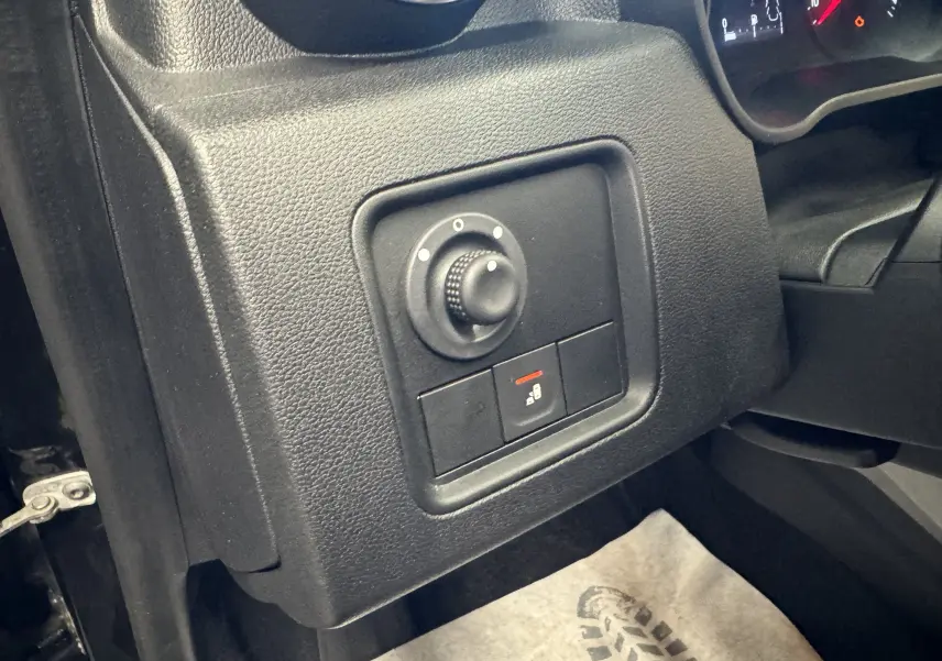 Gros plan sur le tableau de bord noir du Dacia Duster 2022, montrant la molette de réglage des rétroviseurs côté conducteur.