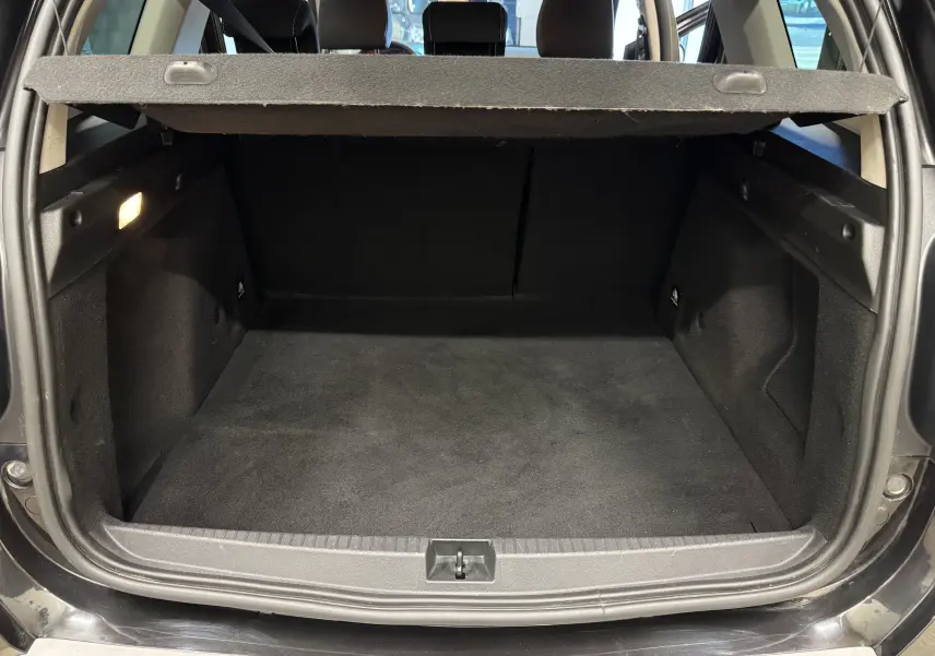 Vue arrière du coffre noir du Dacia Duster 2022, avec cache-bagages relevé et intérieur spacieux visible.