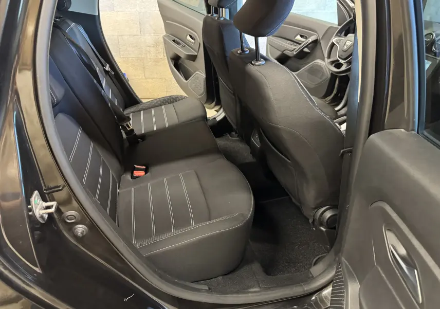 Vue intérieure côté gauche montrant la banquette arrière noire et les sièges avant du Dacia Duster 2022 noir.