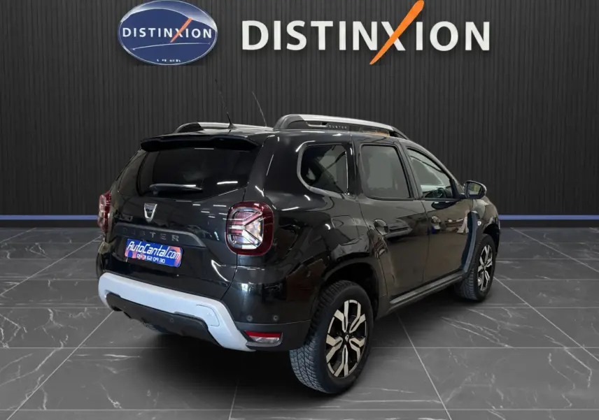 Vue 3/4 arrière droite d'un Dacia Duster noir 2022 avec jantes bi-ton et détails argentés au pare-chocs arrière.