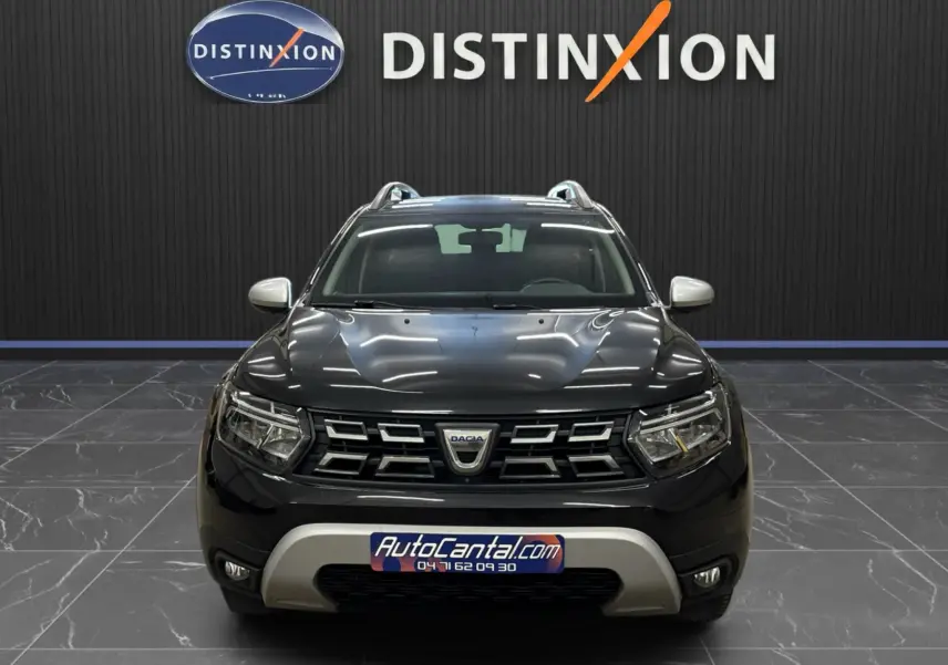 Vue avant d'un Dacia Duster noir 2022 avec calandre chromée et plaques distinctives dans un showroom.