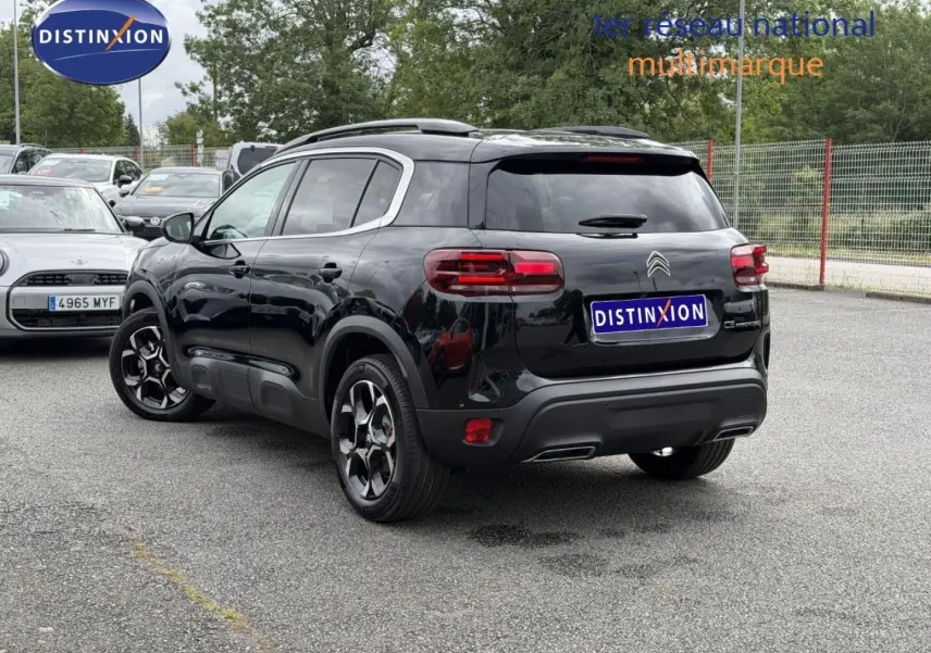 Vue 3/4 arrière droite du Citroën C5 Aircross noir Perla Nera avec barres de toit et jantes alu distinctives.