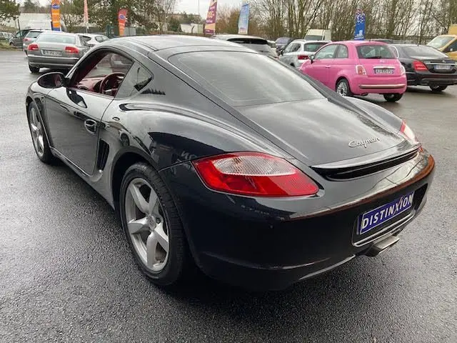 Vue 3/4 arrière droite d'une Porsche Cayman noire de 2008, avec jantes alliage et feux arrière rouges distinctifs.