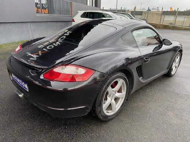 Vue 3/4 arrière droite d'une Porsche Cayman noire de 2008 avec jantes argentées et feux arrière rouges.