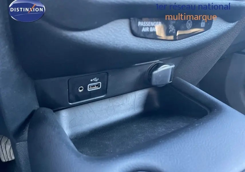 Prise USB et allume-cigare dans le rangement central du Nissan Juke 2024 gris squale métal, intérieur noir.