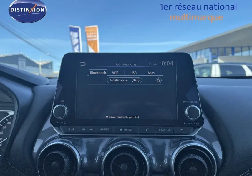 Tableau de bord du Nissan Juke 2024 avec écran tactile central et trois aérateurs ronds en finition gris métal.