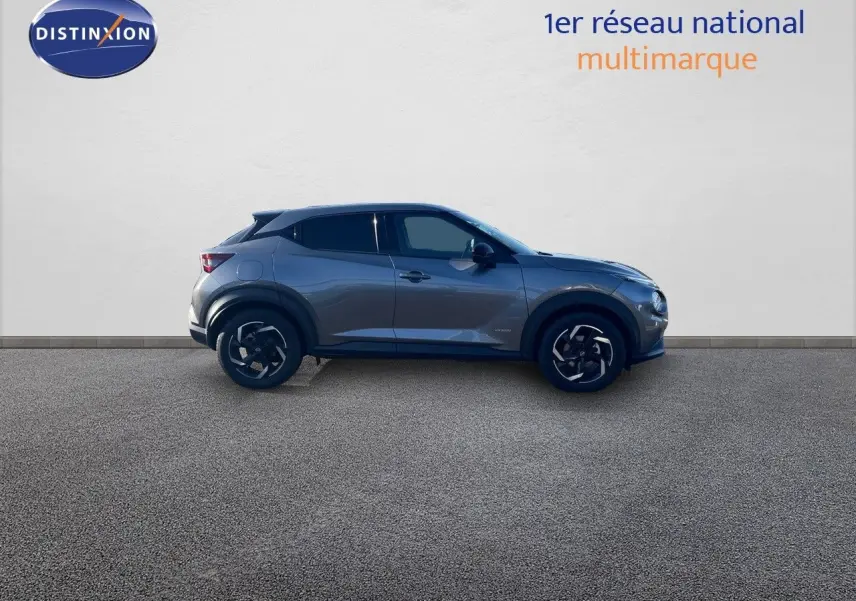 Profil latéral droit d'un Nissan Juke 2024 gris squale métal avec jantes noires et toit noir contrasté.