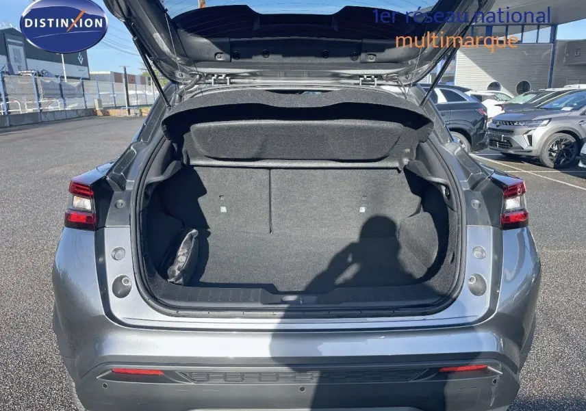 Coffre ouvert vu de l'arrière d'un Nissan Juke 2024 gris squale métal, montrant l'espace de chargement vide.
