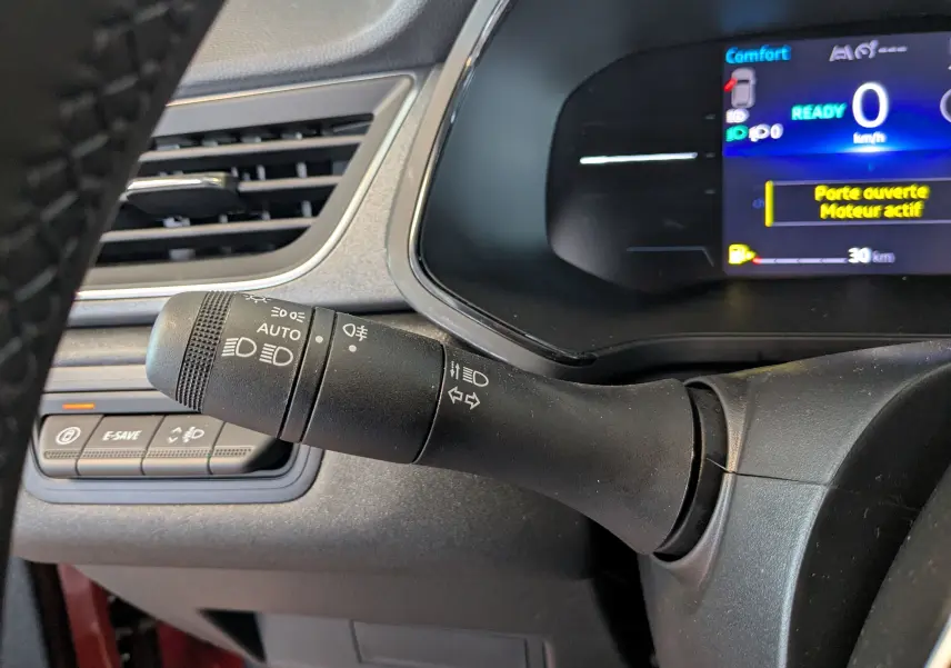 Gros plan sur la commande des phares et clignotants du Renault Captur E-Tech 2025, tableau de bord numérique en arrière-plan.