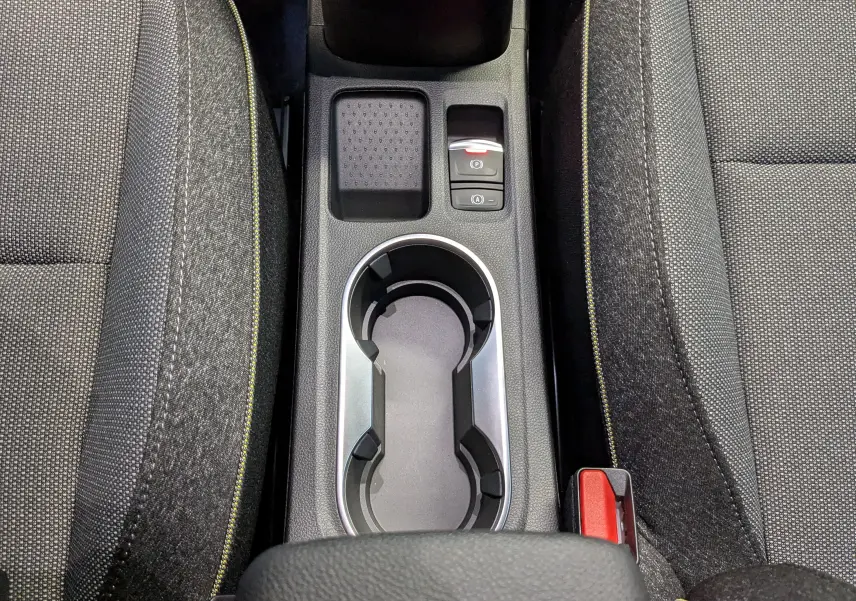 Vue rapprochée de la console centrale du Renault Captur E-Tech 2025, avec porte-gobelets et sièges gris à surpiqûres jaunes.
