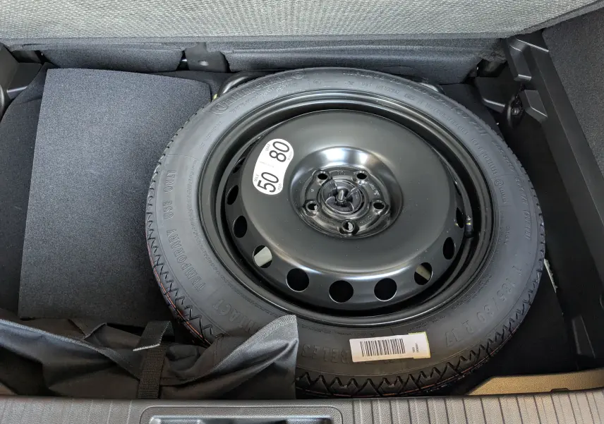 Gros plan sur la roue de secours noire dans le coffre du Renault Captur E-Tech Full Hybrid 2025.