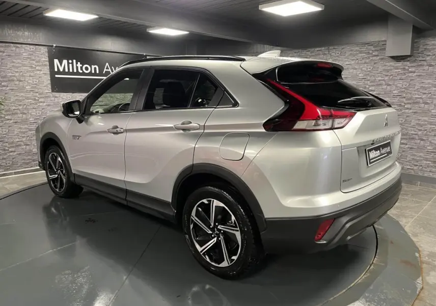 Vue 3/4 arrière droite du Mitsubishi Eclipse Cross gris métallisé avec jantes alliage bi-ton et toit noir en intérieur showroom.