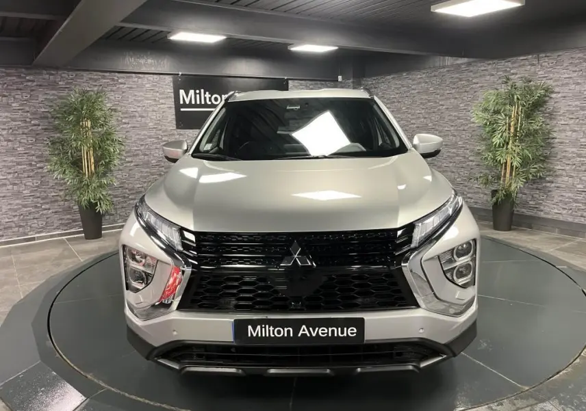 Vue frontale d'un Mitsubishi Eclipse Cross gris métallisé avec calandre noire et éclairage LED distinctif dans un showroom.